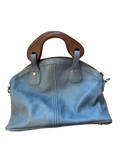 Blue handbag with wooden handle on a wooden surface