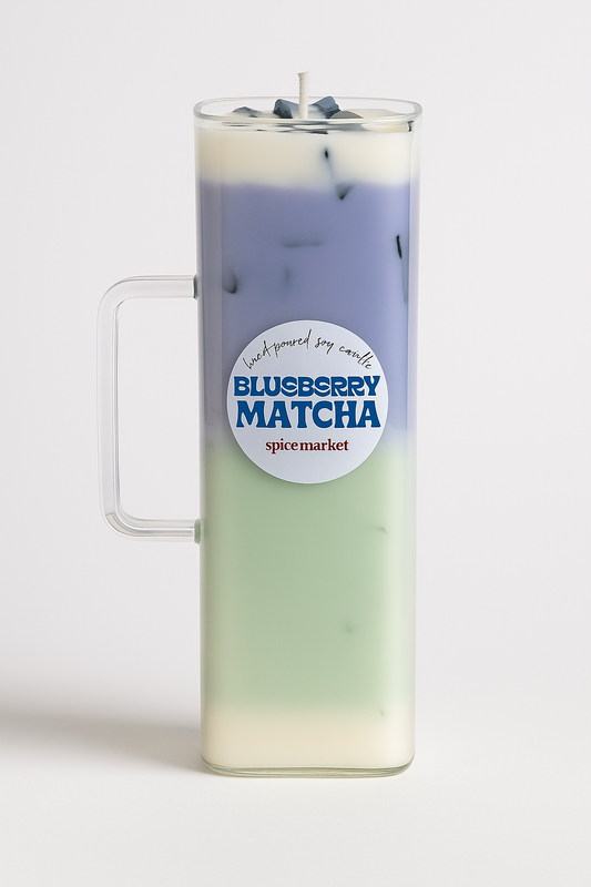Candle in a glass mug with blueberry matcha flavor label on a white background